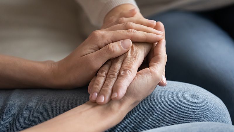 younger person holding elderly persons hands
