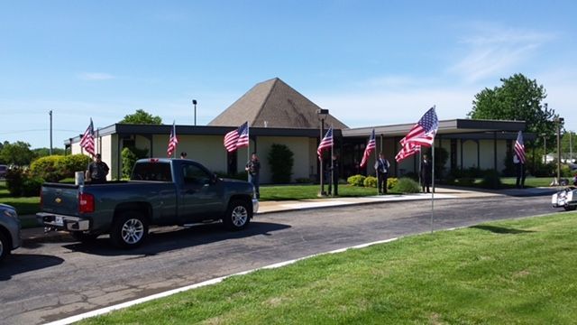 A truck is parked in front of a building with american flags