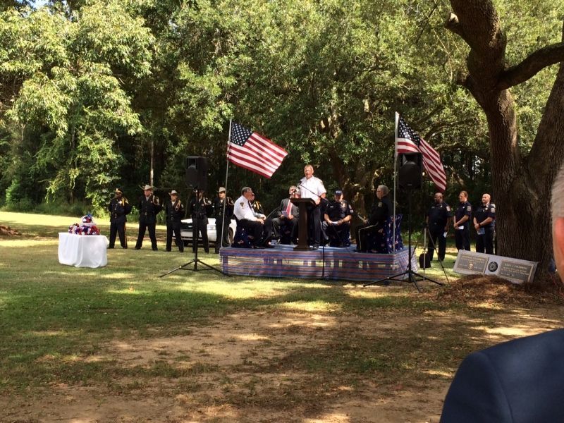 A man is standing at a podium in front of a group of people holding american flags.