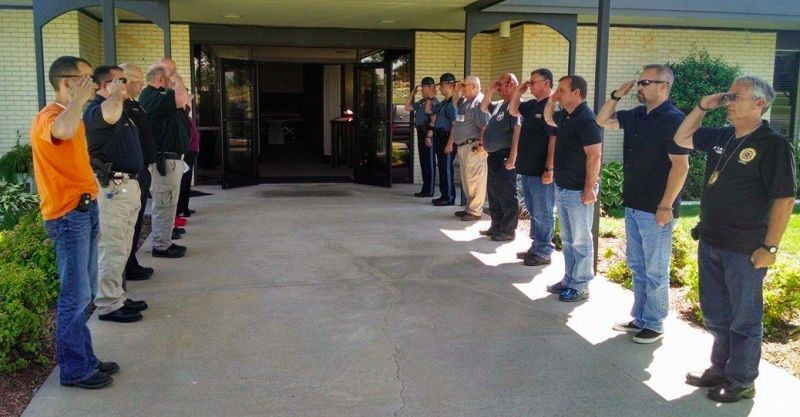 A group of men are saluting in front of a building