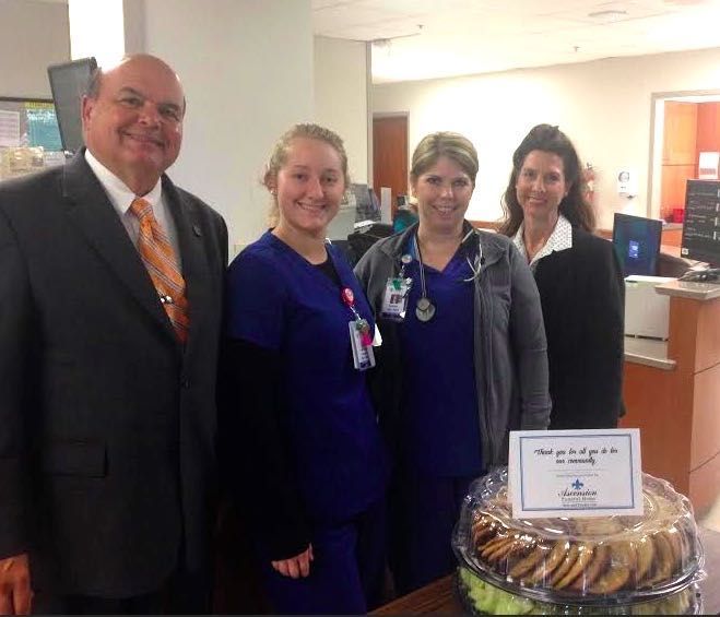 A man in a suit and tie stands next to two nurses