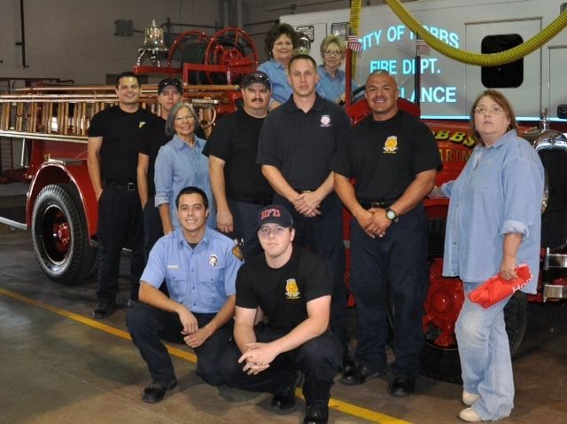 A group of firefighters pose for a picture in front of a fire truck