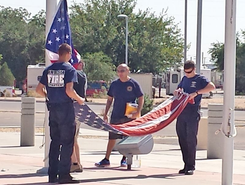 A group of firefighters are holding an american flag