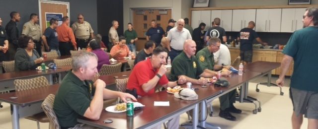 A group of people are sitting at tables in a room eating food.