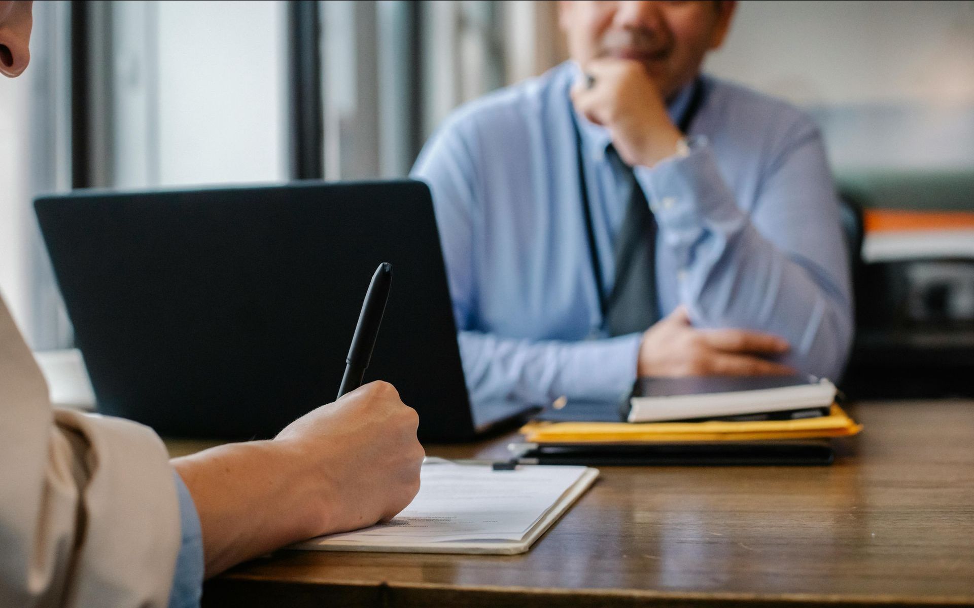 A man and a woman are sitting at a table with a laptop.