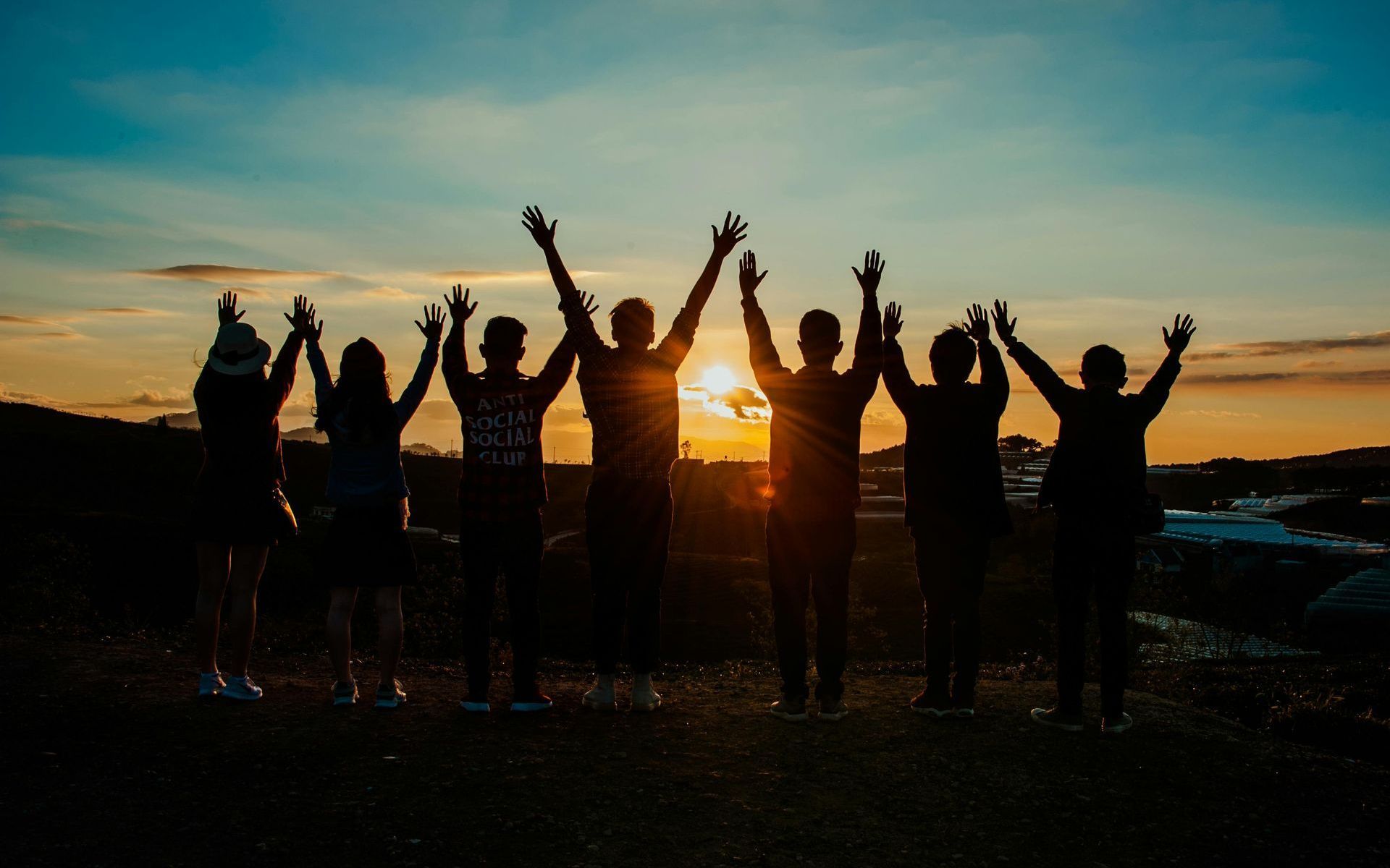 A group of people are standing next to each other with their hands in the air.
