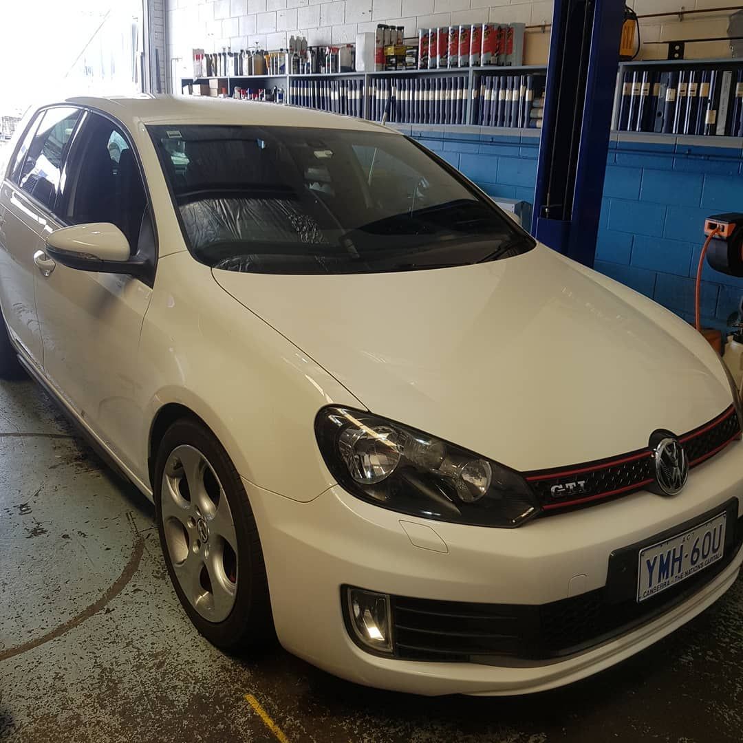 A White Volkswagen Car Is Parked in A Garage — Latin Motors in Fyshwick, ACT