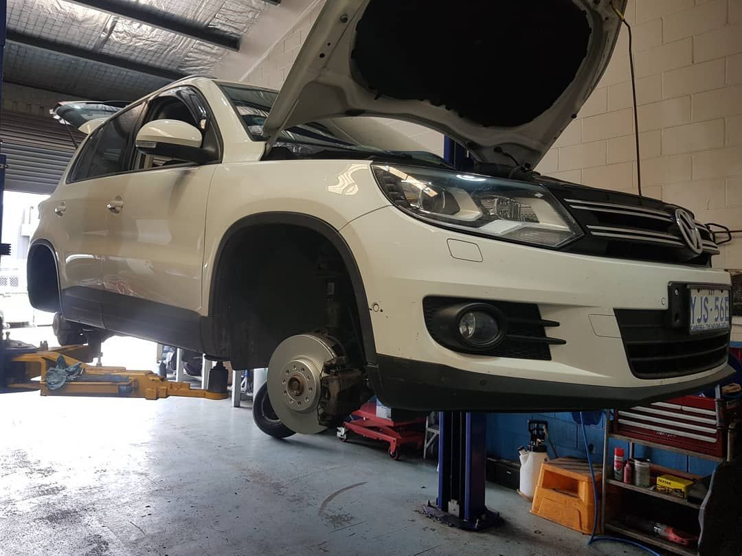 A White Volkswagen Tiguan Is Sitting on A Lift in A Garage — Latin Motors in Fyshwick, ACT