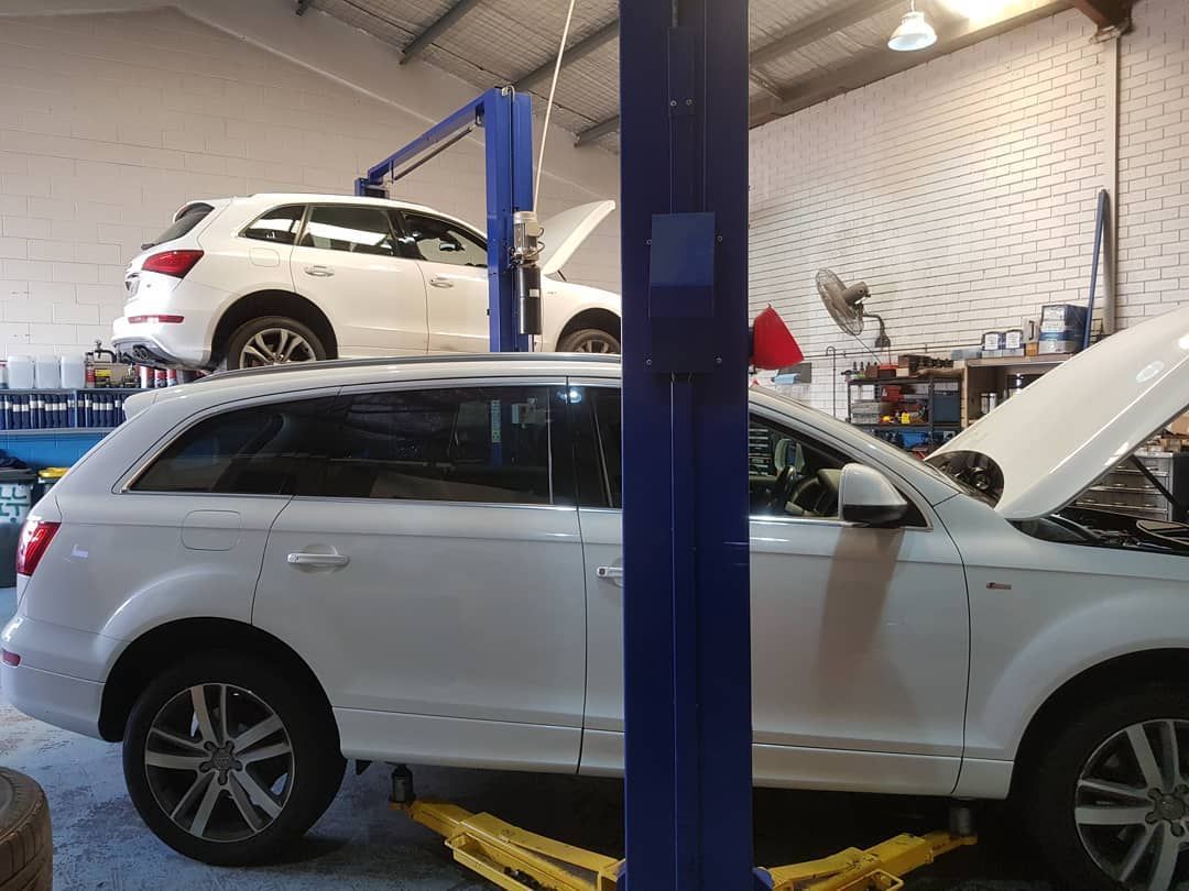 A White Suv Is Sitting on A Lift in A Garage — Latin Motors in Fyshwick, ACT