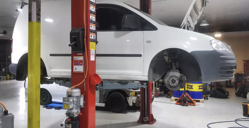 A White Van Is Sitting on A Lift in A Garage — Latin Motors in Fyshwick, ACT