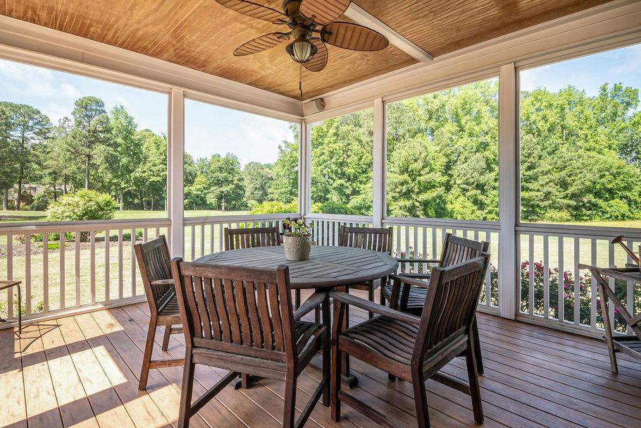 Screened-in porch with wooden dining table and ceiling fan.