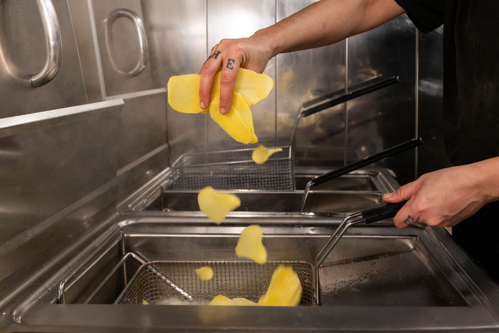 Una persona sta cucinando le patate in una friggitrice.