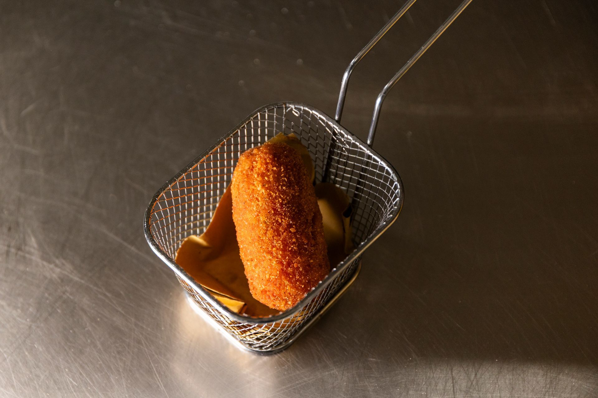 Primo piano di un cibo fritto in un cestino su un tavolo.