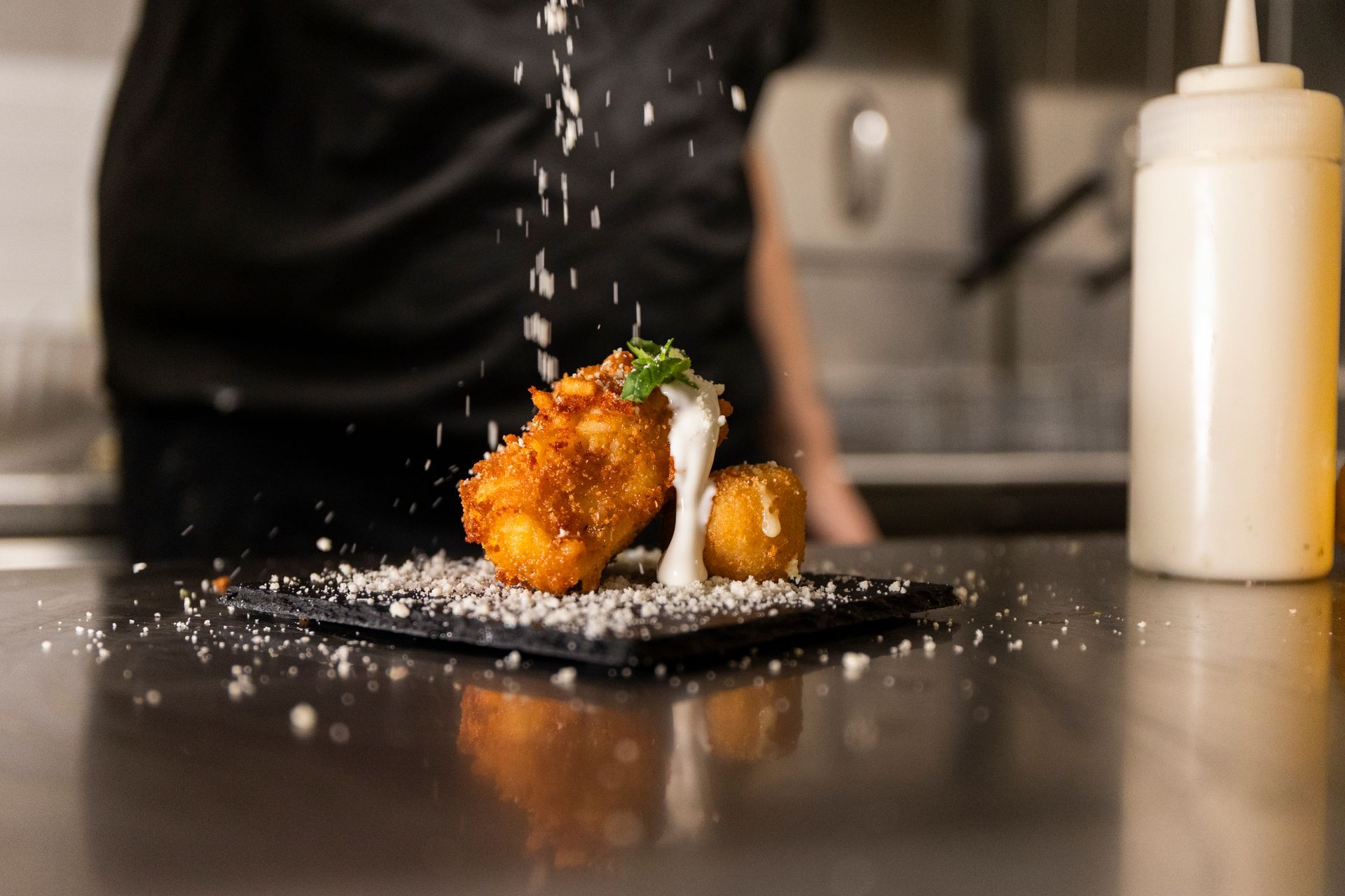 Un primo piano di un piatto di cibo con una bottiglia di salsa sullo sfondo.
