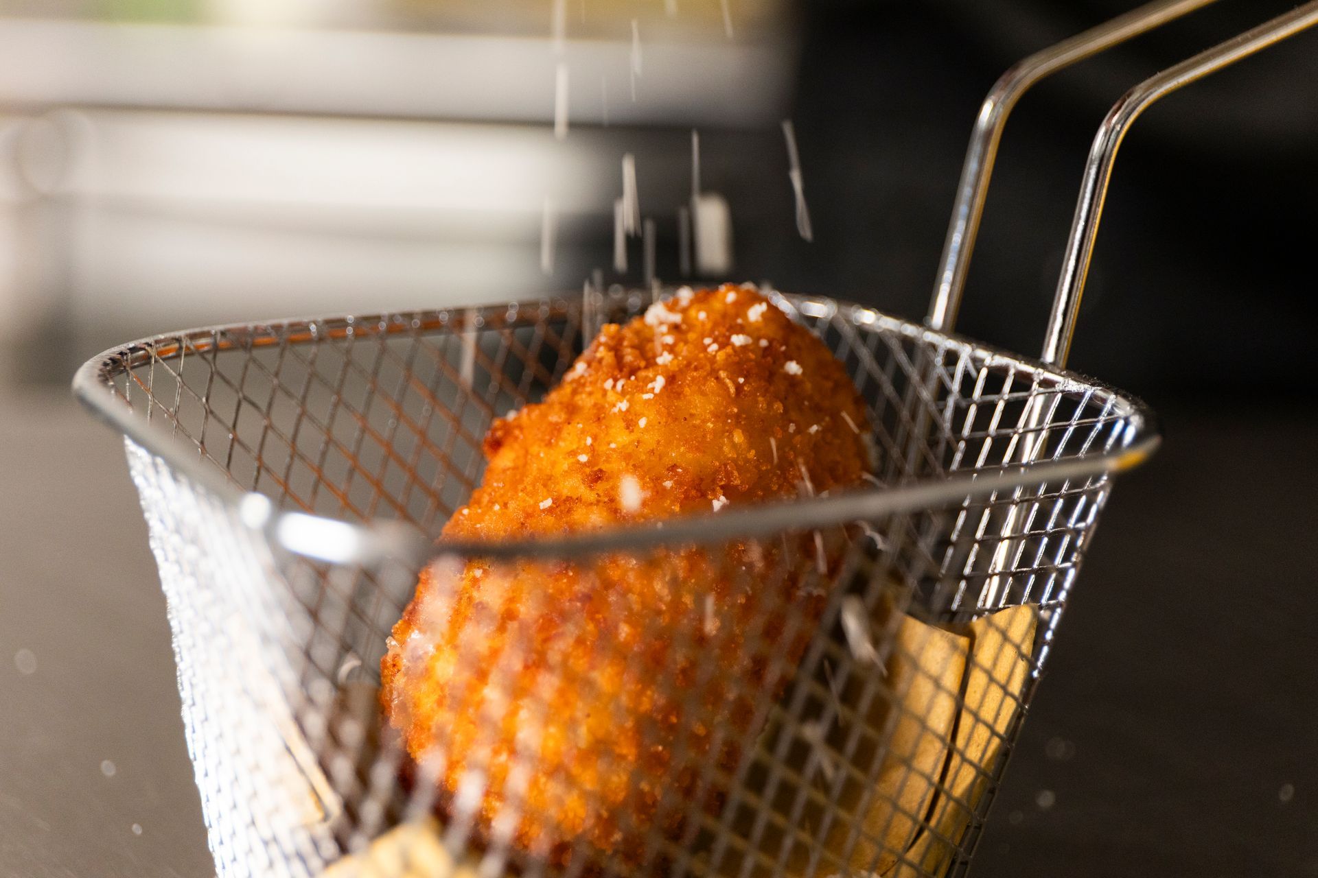 Primo piano di un alimento fritto in un cestello per friggere.