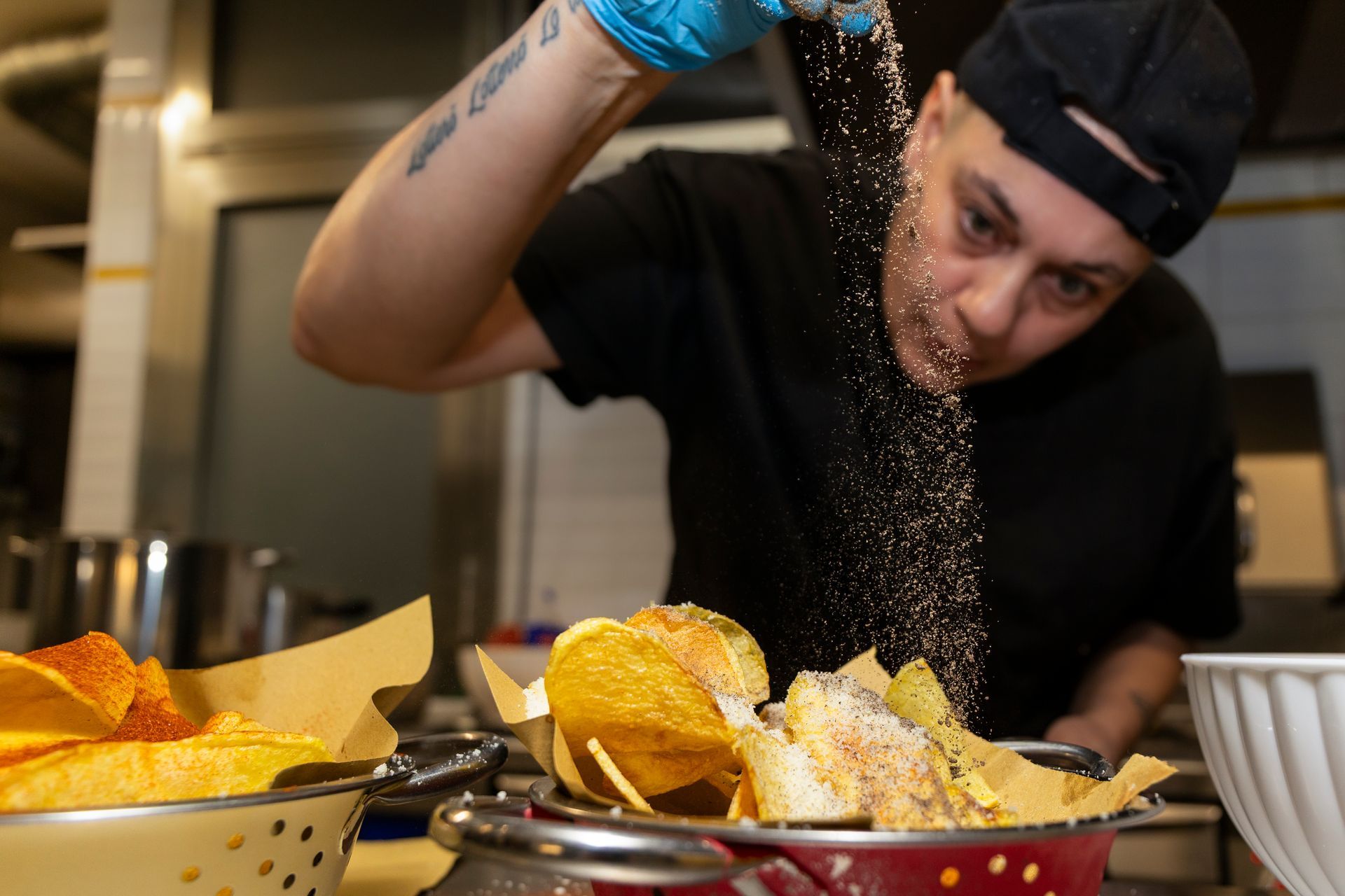 Un uomo sta spargendo sale su una ciotola di patatine.