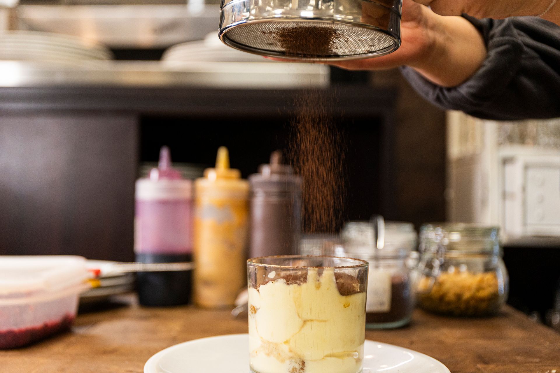 Una persona sta cospargendo di zucchero a velo un dolce in un bicchiere.