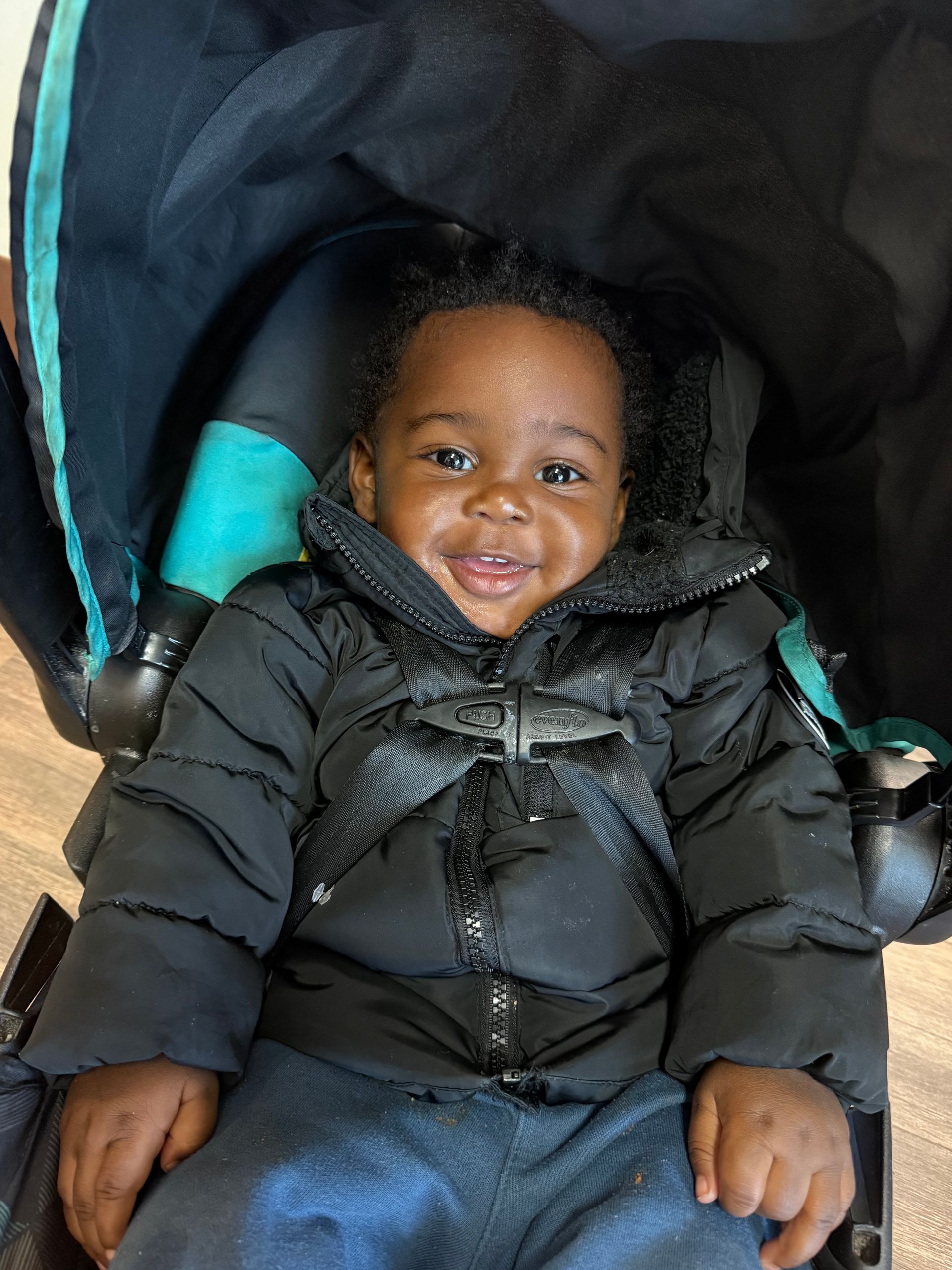 Children and a woman play on a wooden floor, drawing and interacting with toys in a brightly lit room.