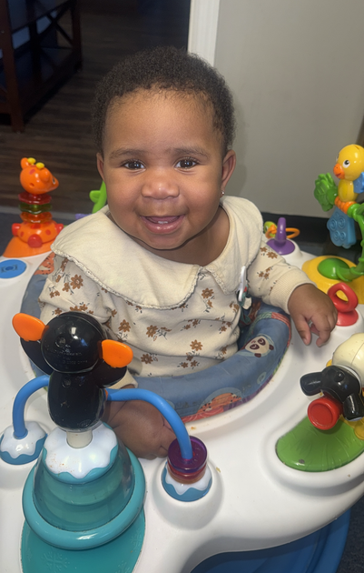 Bright classroom with art supplies on tables and shelves. Colorful paintings on walls.