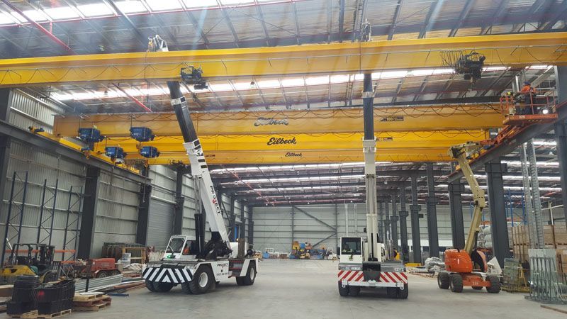 A large warehouse with a crane and a forklift in it.