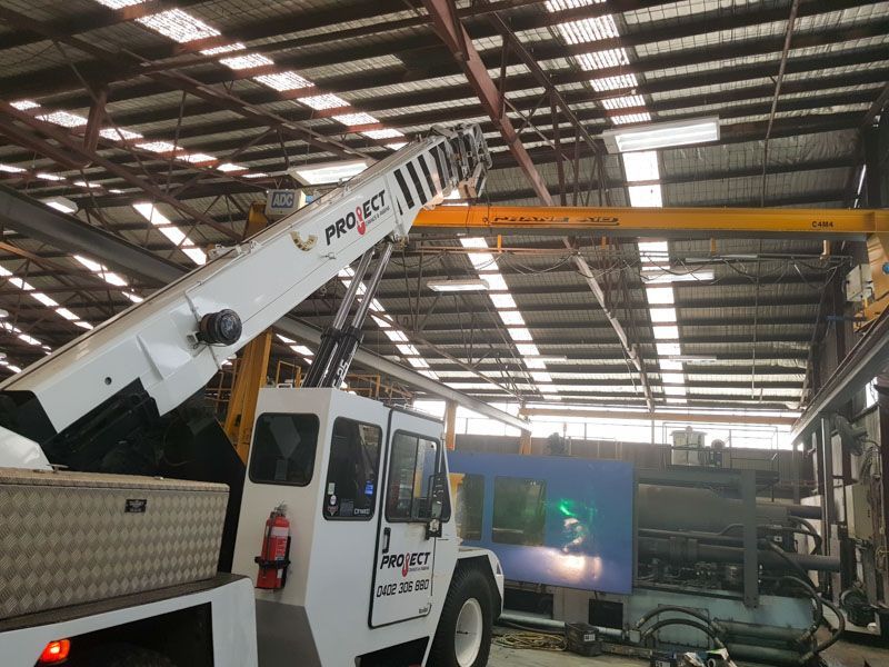 A truck with a crane attached to it is in a warehouse.