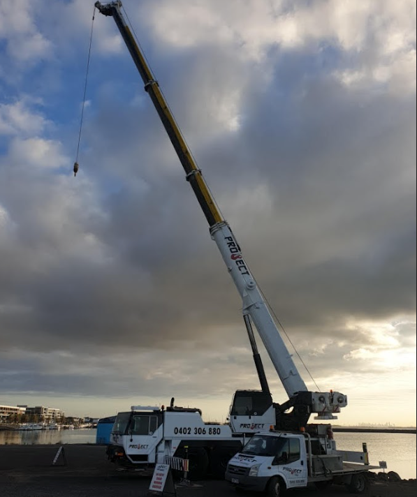 A large crane is parked in front of a body of water.