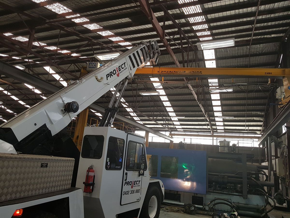 A white truck with a crane attached to it is in a warehouse.