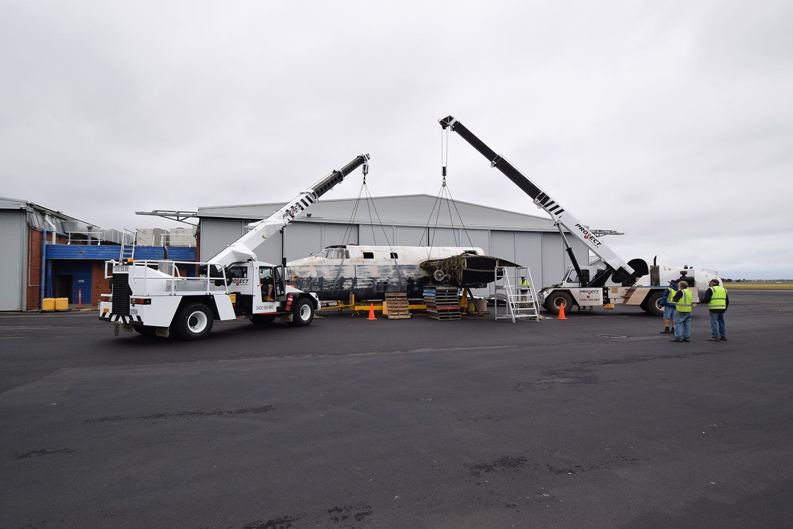 A white truck with a crane attached to it is parked in front of a building.