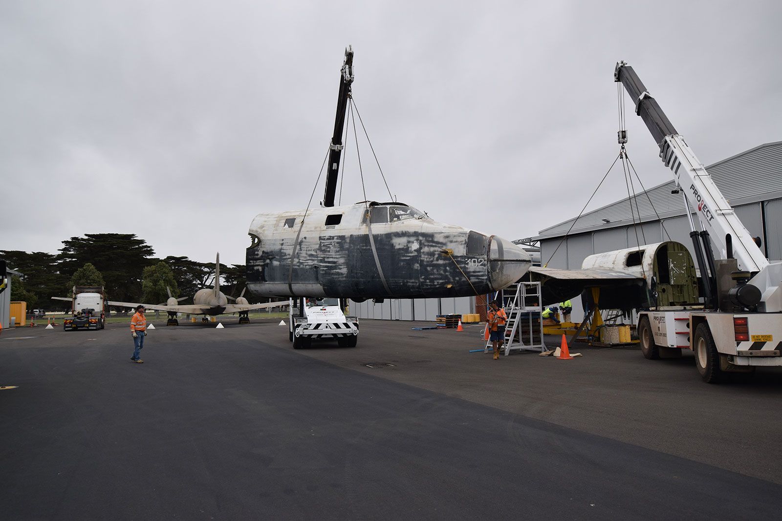 A large boat is being lifted by a crane in a parking lot.