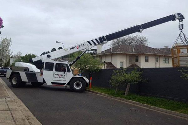 A truck with a crane attached to it is parked on the side of the road
