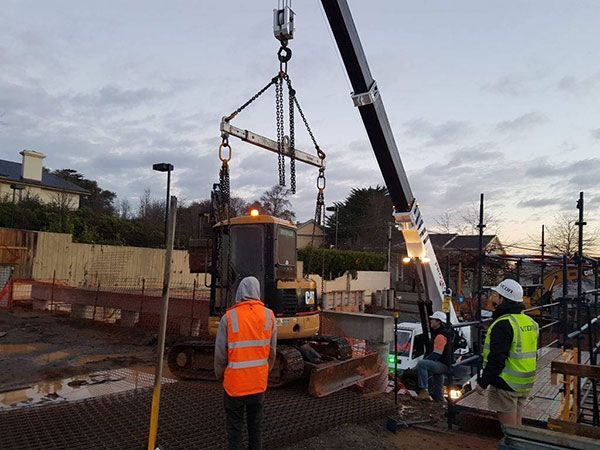 A crane is lifting a bulldozer on a construction site.