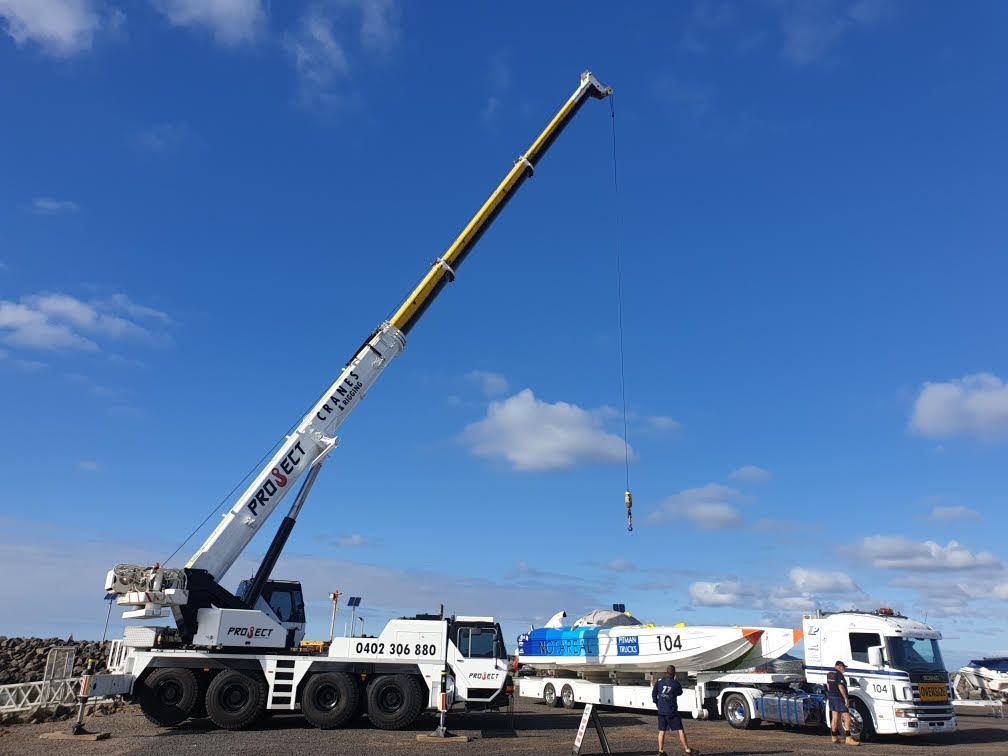 A large crane is lifting a boat on a trailer.