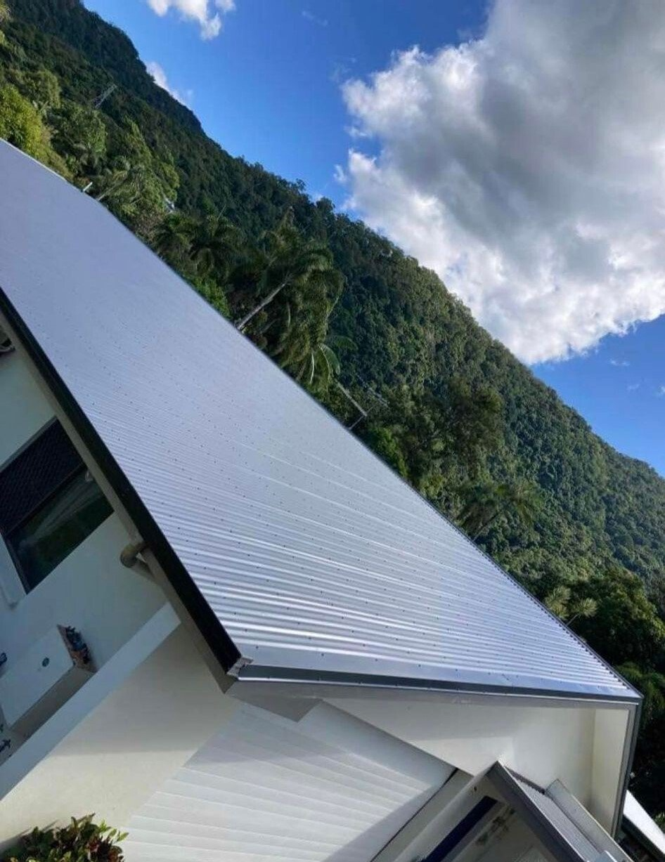 A house with a white roof and a mountain in the background