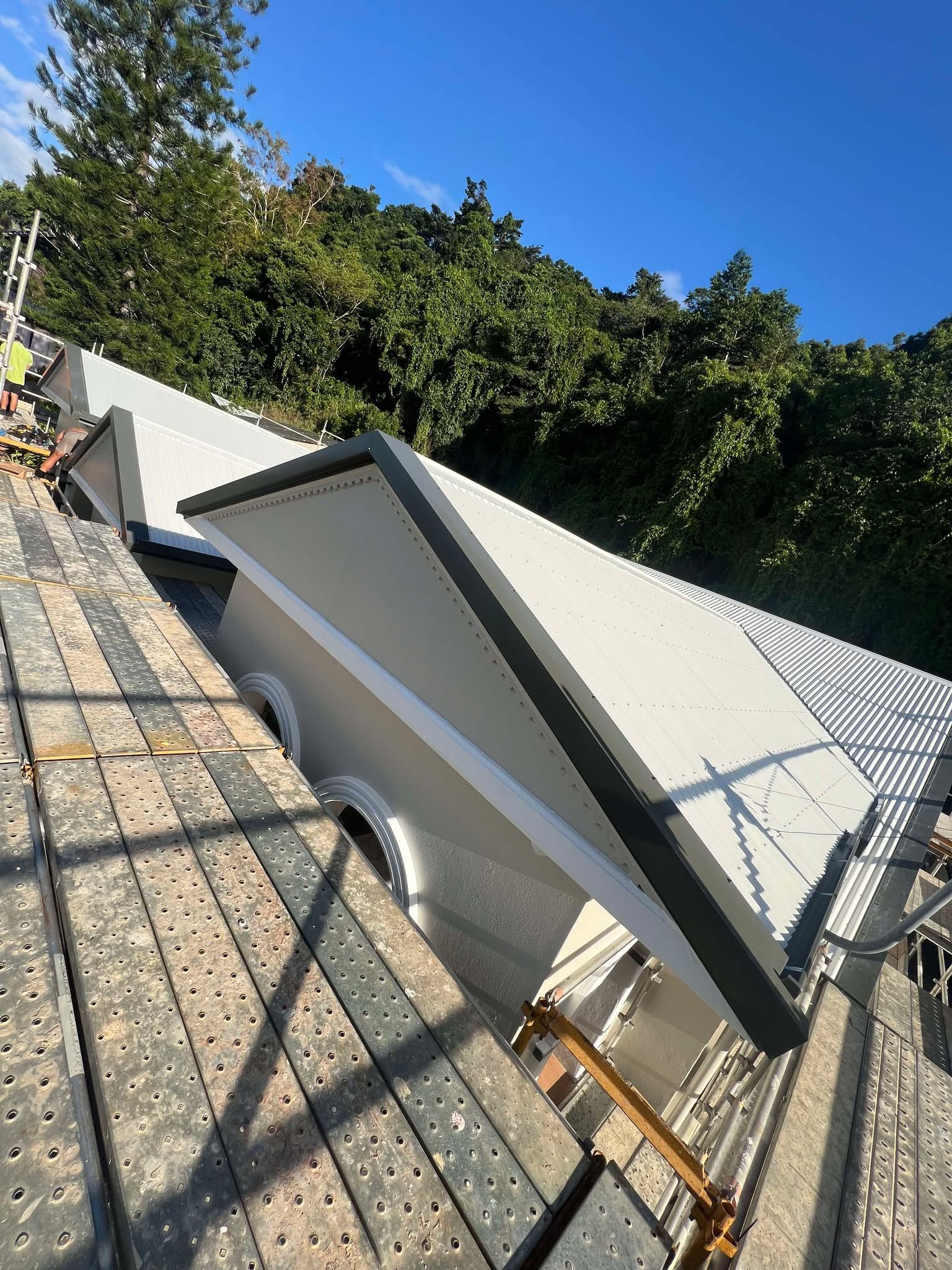 A roof is being built on a scaffolding with trees in the background.
