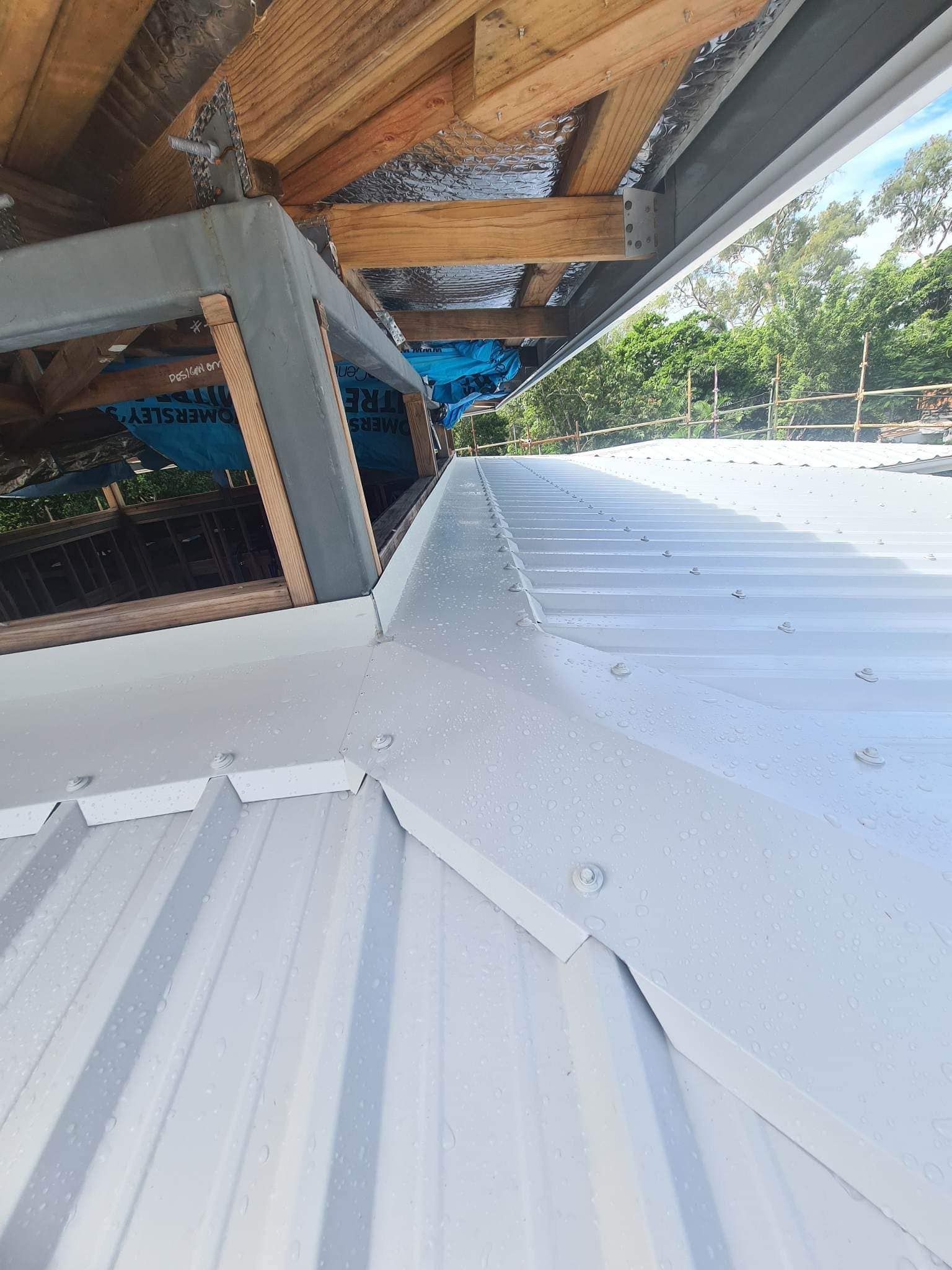 The roof of a building with a triangle shaped roof and trees in the background.