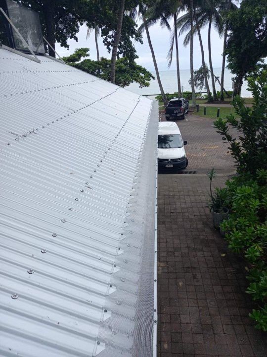 A white van is parked in front of a white roof.
