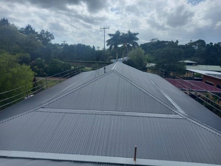 The roof of a building with a triangle shaped roof and trees in the background.