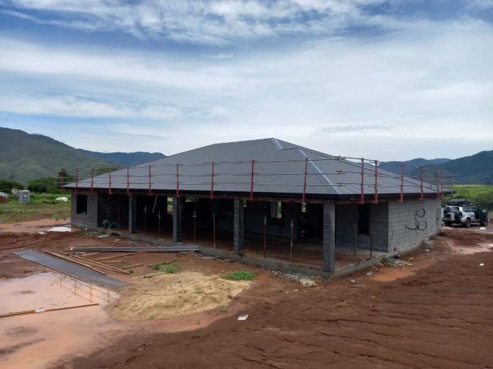 A house is being built in a dirt field with mountains in the background.
