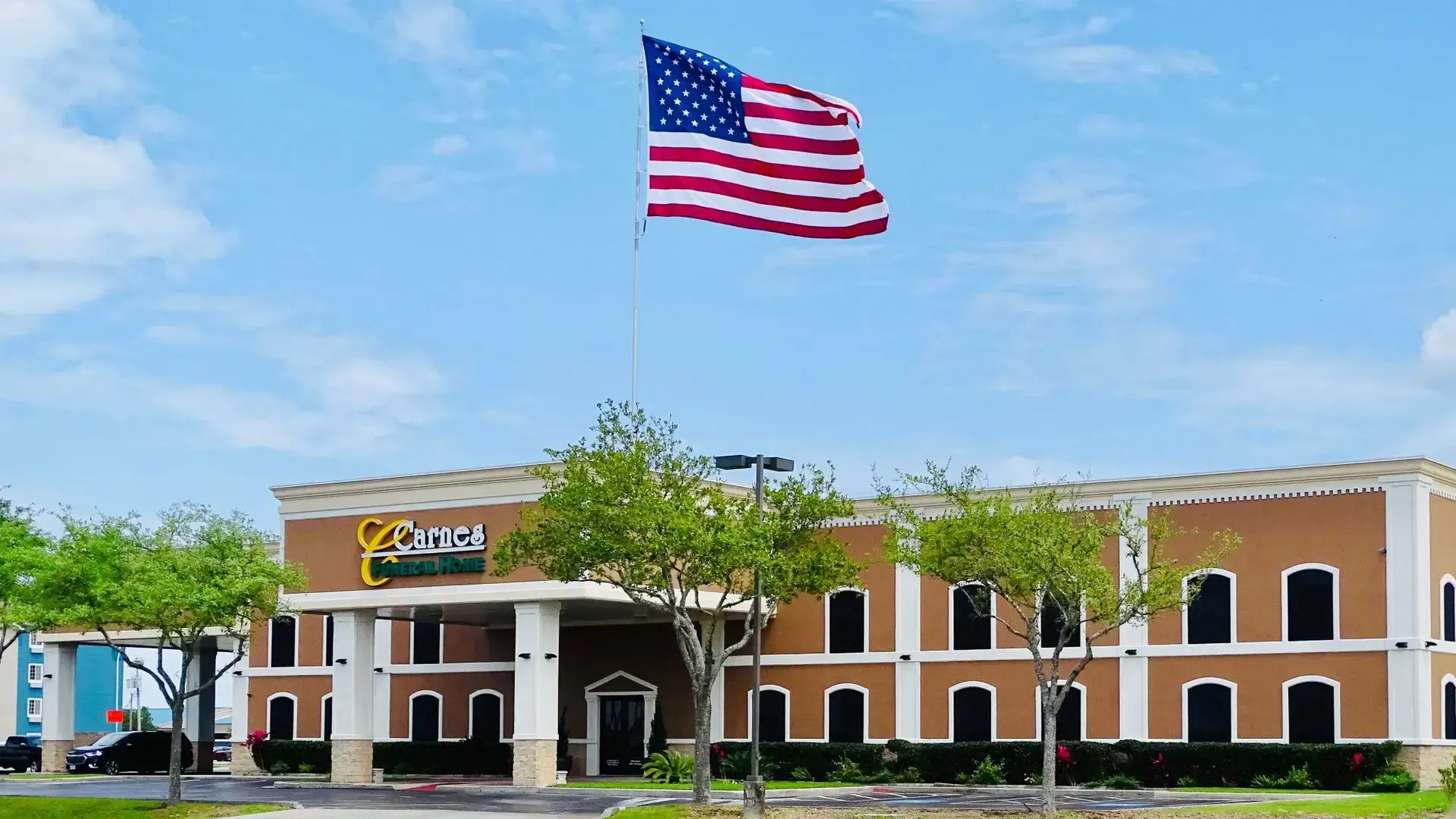 A brown two-story hotel with a large American flag waving in the wind.