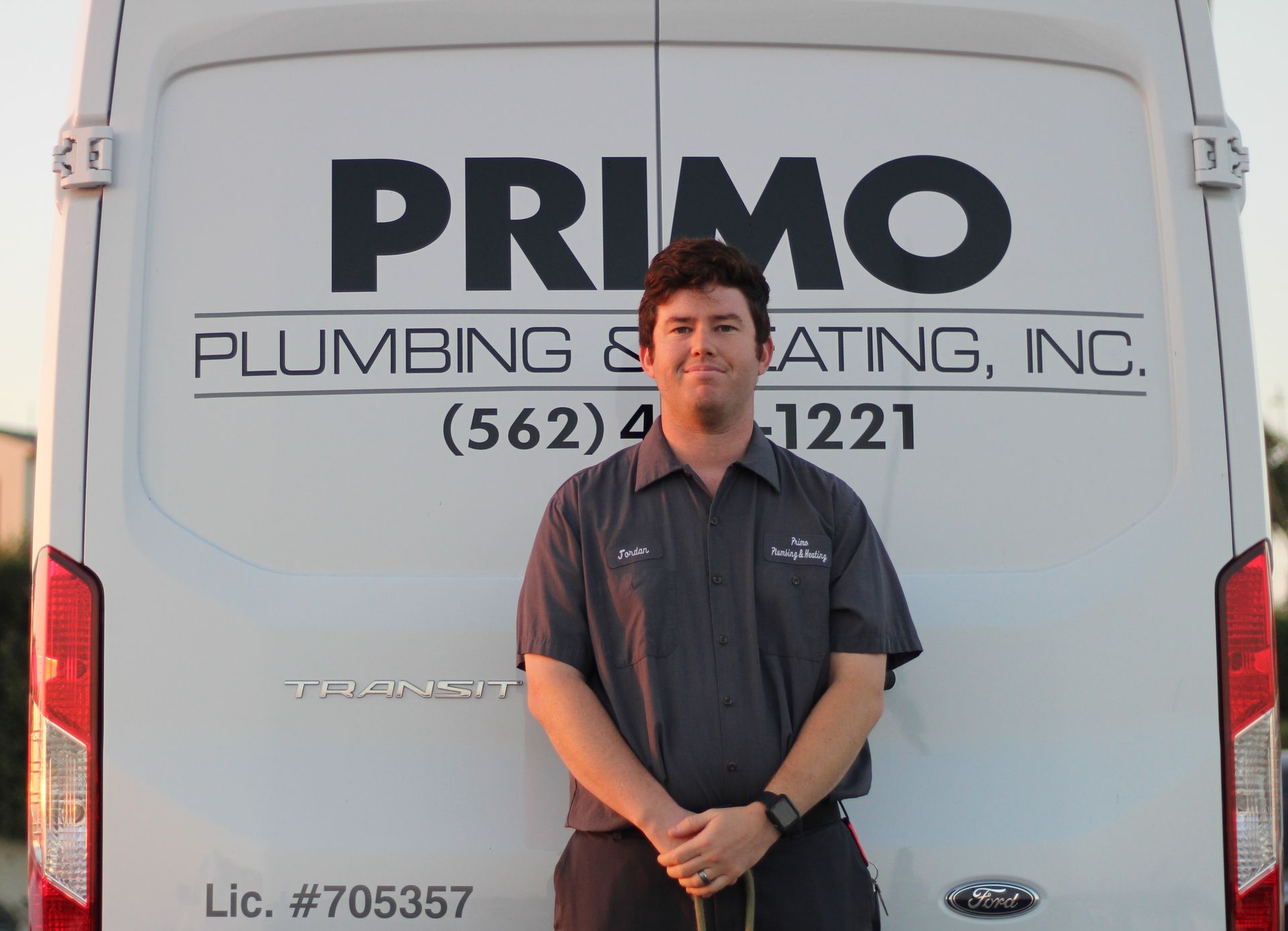 Primo Plumbing A man is standing in front of a primo plumbing and heating van
