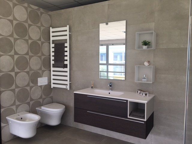 Bagno moderno con doppio lavabo, termoarredo, bidet e pareti piastrellate.