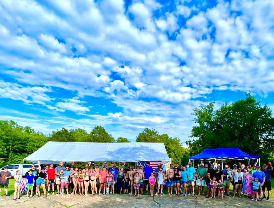 A large group of people are posing for a picture under a tent.