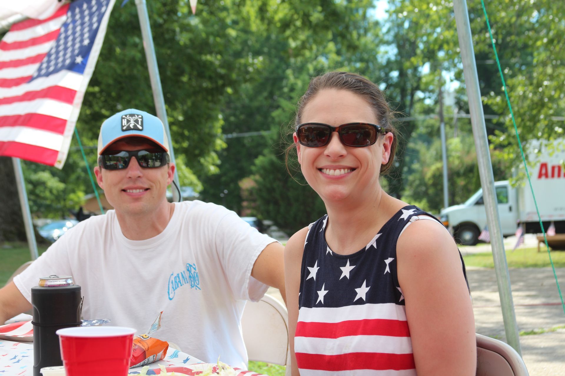 A man and a woman are sitting at a table under an american flag.