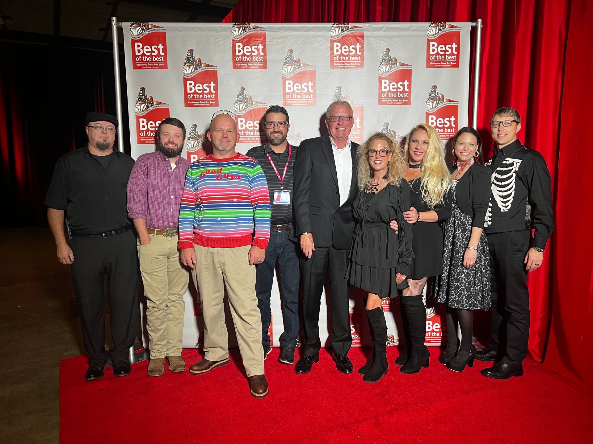 A group of people are posing for a picture on a red carpet.