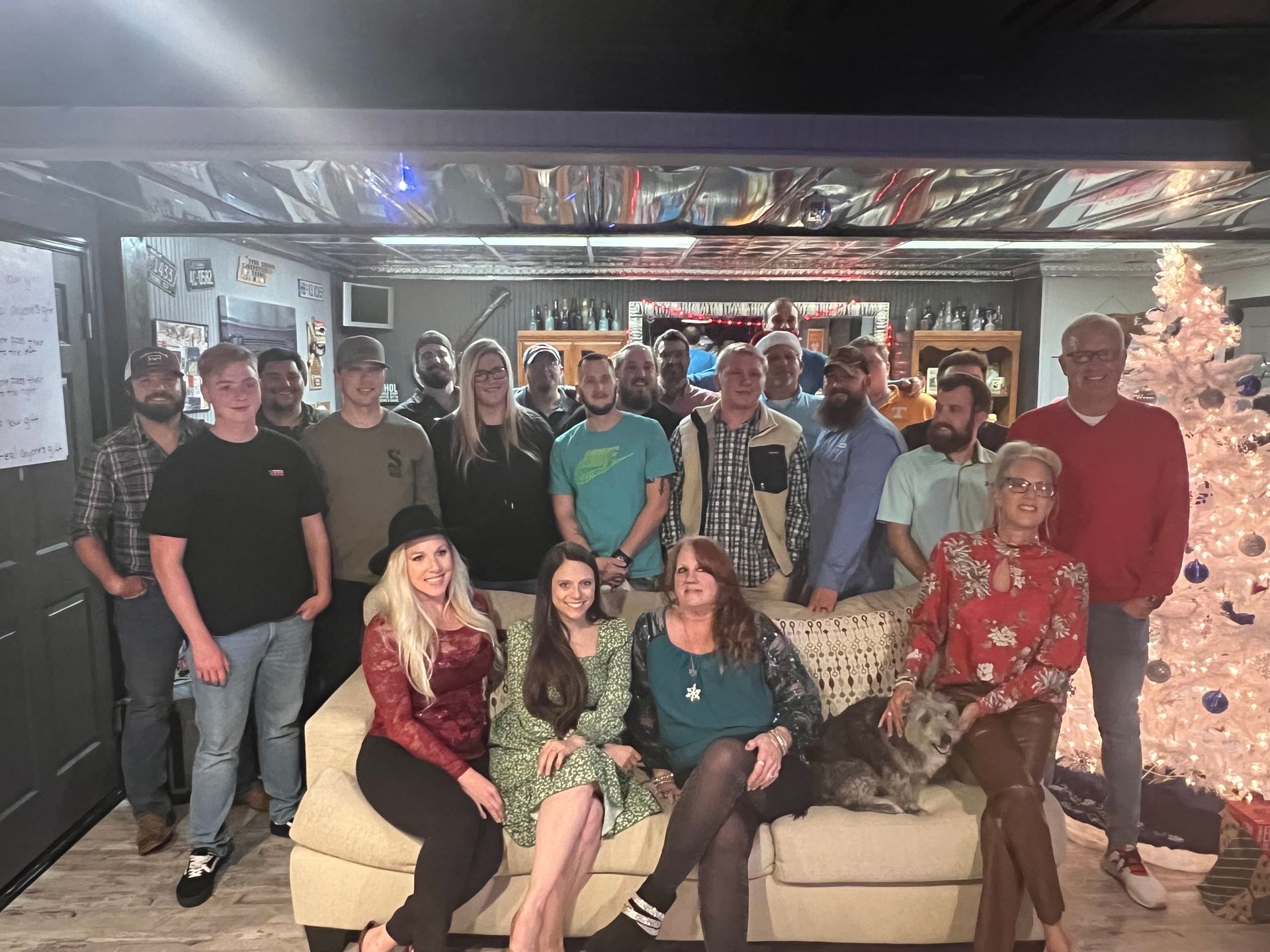A group of people are posing for a picture in front of a christmas tree.