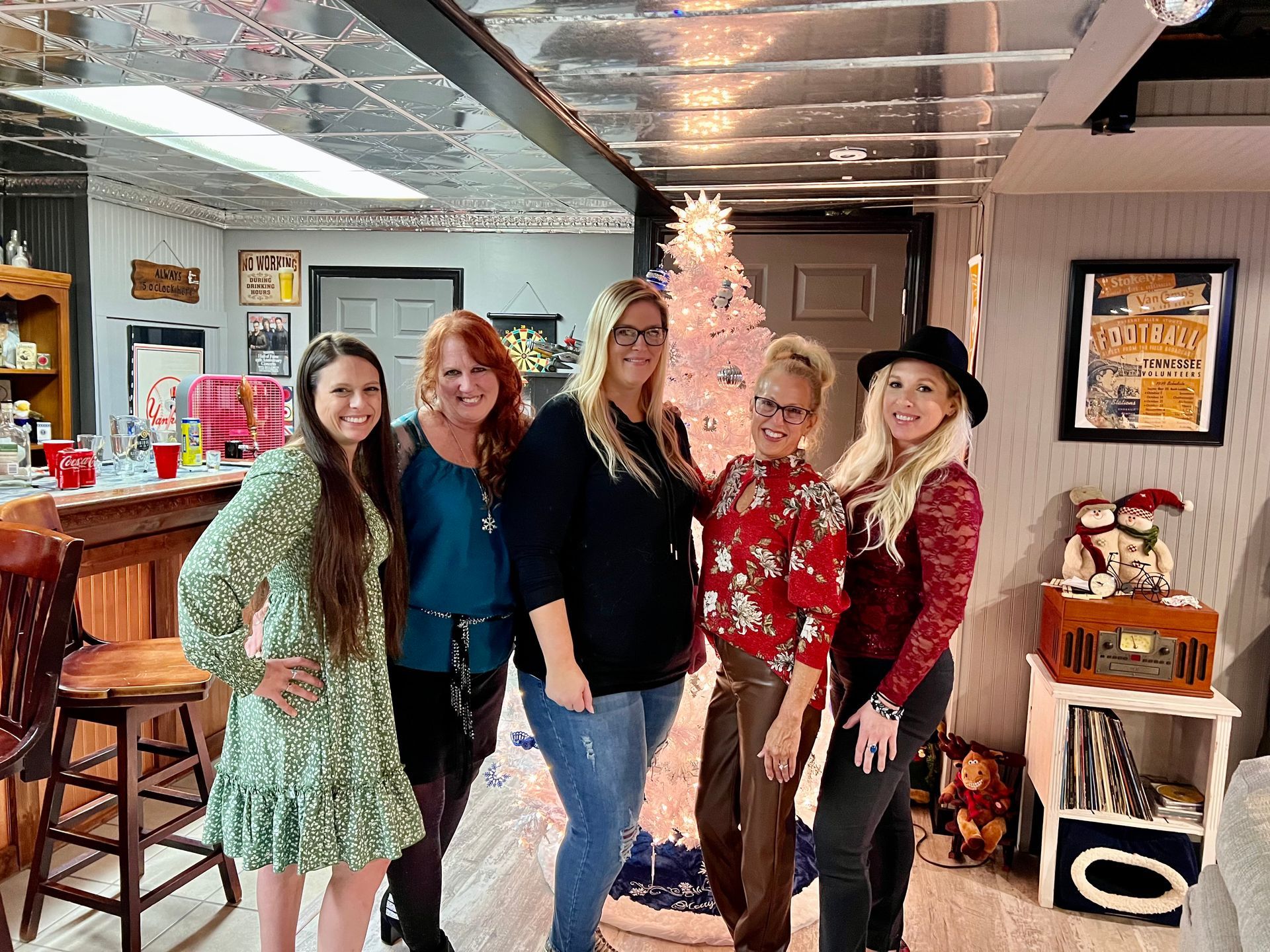 A group of women are posing for a picture in front of a christmas tree.