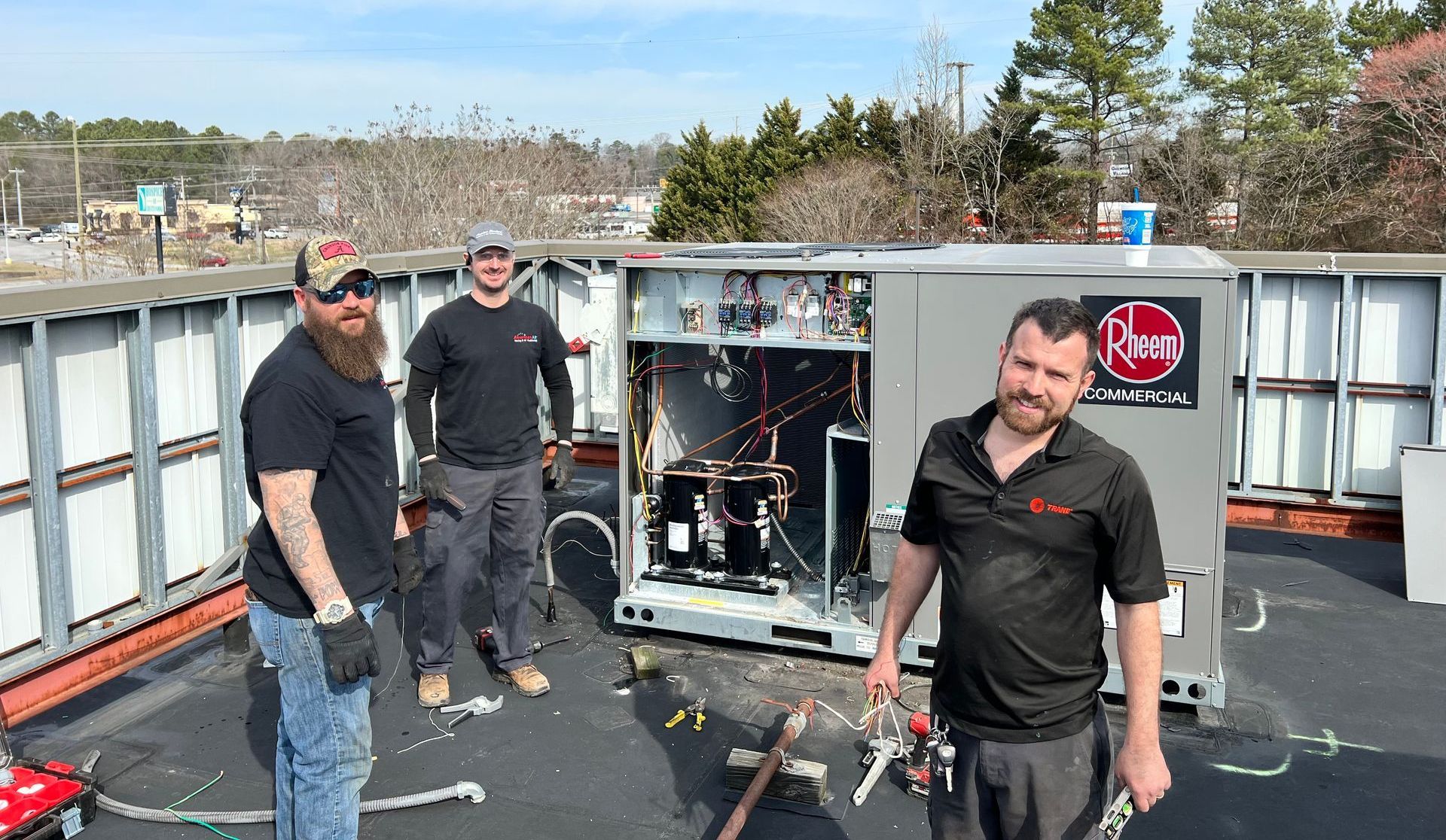 A group of men are standing next to a machine on a roof.