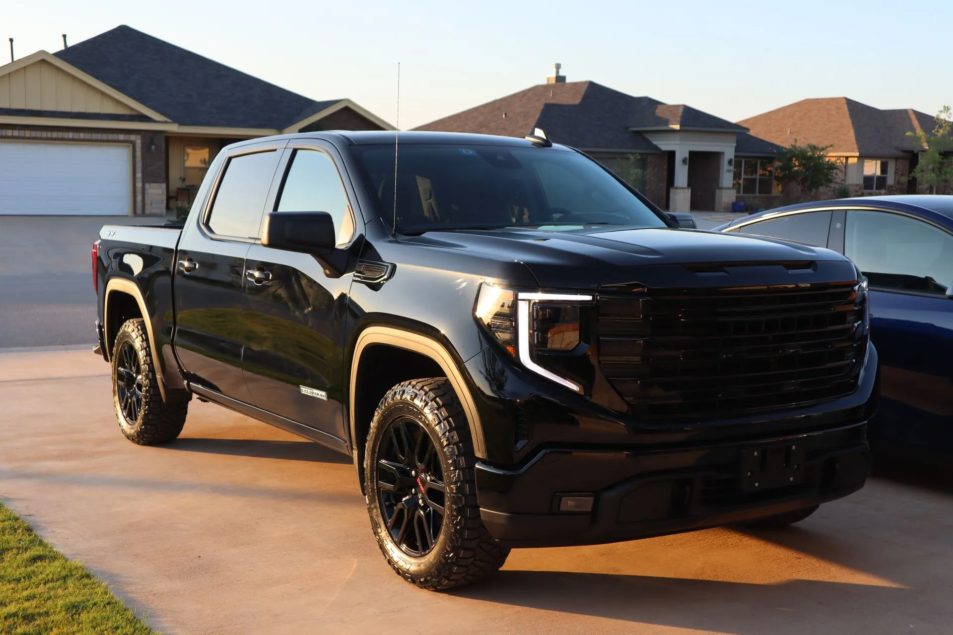 White Mercedes-AMG GT 4-door coupe parked in front of a concrete wall; chrome rims, black accents.
