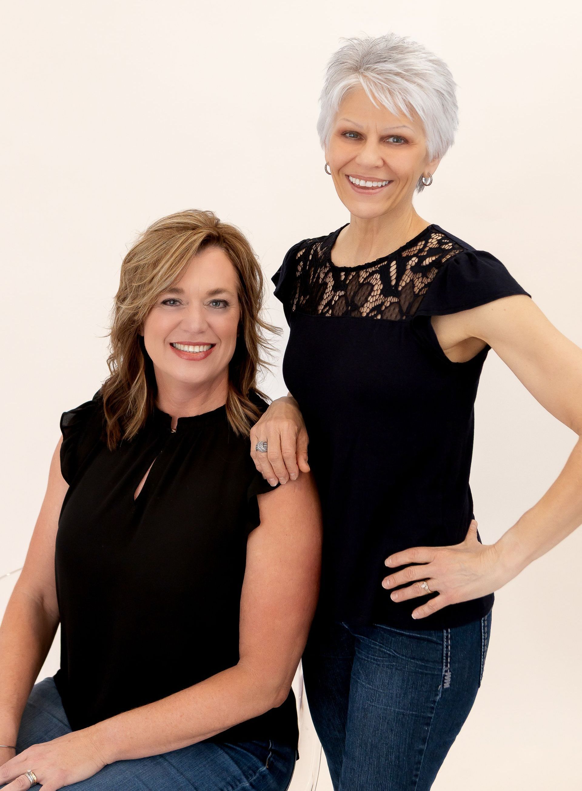 A woman is laying on a yoga mat with a little girl on her back.