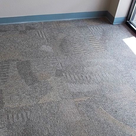 Gray patterned commercial carpet with blue baseboard and window trim.